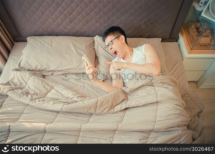 Angry Asian man blaming on the phone on bed