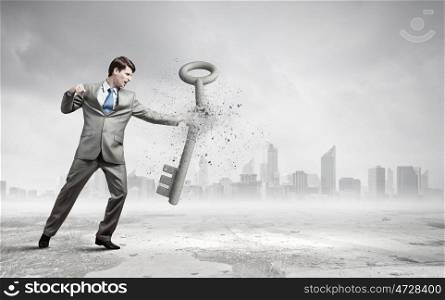 Angry businessman crashing stone key with punch. Determined and powerful