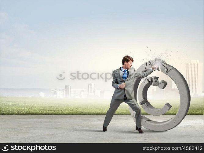 Angry businessman crashing stone trademark with karate kick. Copyright concept