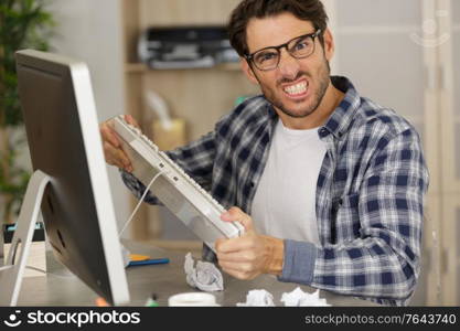 angry businessman holding computer keyboard