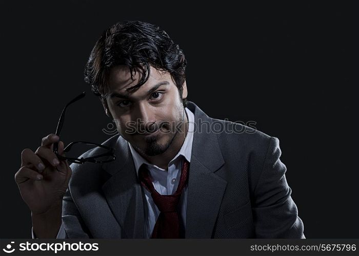 Angry businessman holding glasses over black background