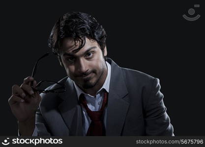 Angry businessman holding glasses over black background