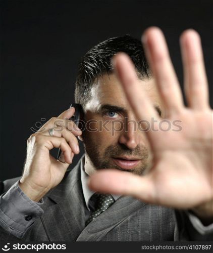 Angry businessman saying stop with hand,talking to a mobile phone