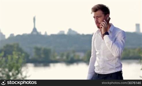 Angry businessman shouting on the phone while having conversation with his employee outdoors