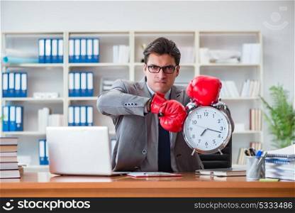 Angry businessman with boxing gloves in time management concept