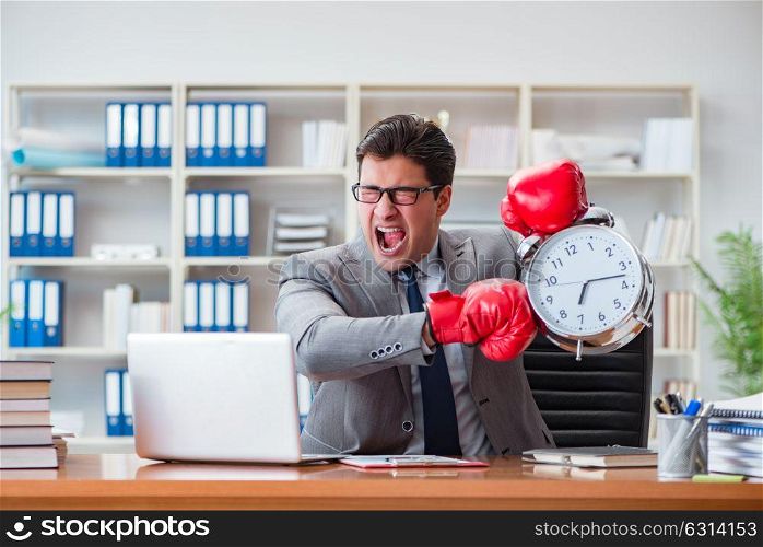 Angry businessman with boxing gloves in time management concept