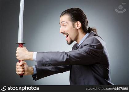 Angry businessman with sword in dark room