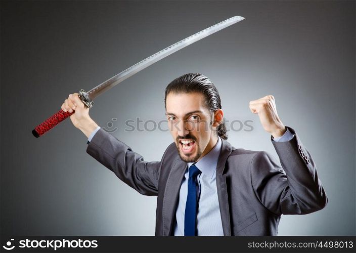 Angry businessman with sword in dark room