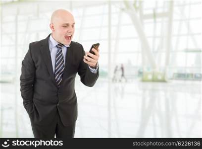Angry businessman yelling into a cellphone, at the office