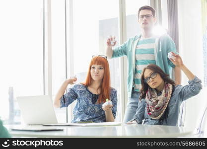 Angry businesspeople throwing paper balls in creative office