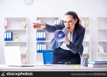 Angry businesswoman yelling with loudspeaker in office