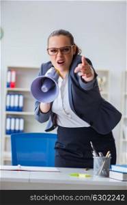 Angry businesswoman yelling with loudspeaker in office. The angry businesswoman yelling with loudspeaker in office