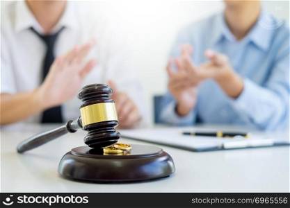 Angry couple arguing telling their problems to Judge gavel deciding on marriage to conclude an agreement on the divorce. They quarrel and argue with each other.