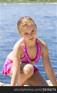 Angry girl on the riverbank in pink swimsuit