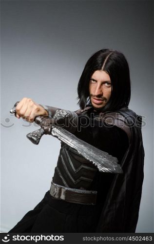 Angry knight with sword against dark background