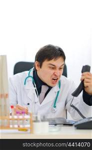 Angry medical doctor shouting in phone handset