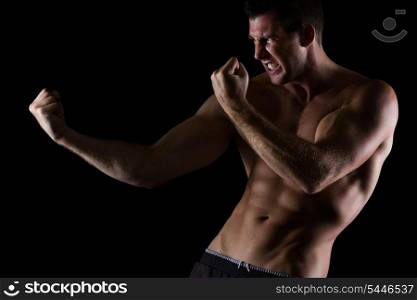 Angry muscular man in attack pose on black