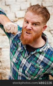 Angry red haired hipster man with blue plaid shirt