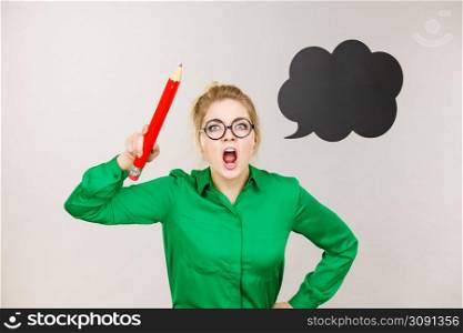Angry screaming teacher looking elegant woman wearing dark tight skirt and shirt holding big oversized pencil, black thinking or speech bubble next to her.. Angry teacher woman holding big pencil