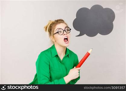 Angry screaming teacher looking elegant woman wearing dark tight skirt and shirt holding big oversized pencil, black thinking or speech bubble next to her.. Angry teacher woman holding big pencil