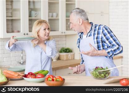 angry senior couple fighting with each other kitchen