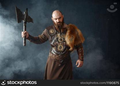 Angry viking with axe, martial spirit, barbarian image. Ancient warrior in smoke. Angry viking with axe, martial spirit, barbarian