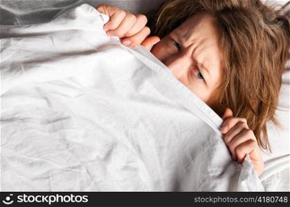angry woman is lying in bed under blanket and doesn&acute;t want to wake up