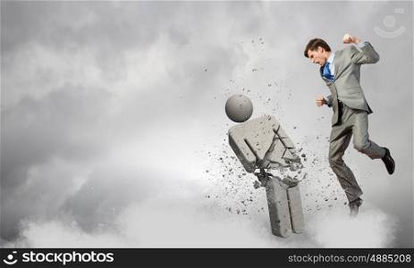 Angry young businessman fighting with stone opponent. No competitors on my way
