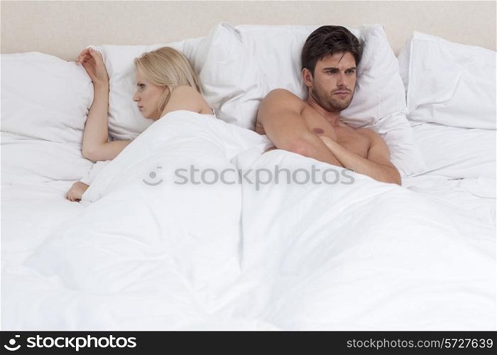 Angry young couple lying in bed
