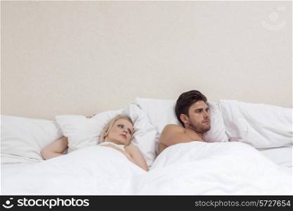 Angry young man ignoring woman in bed