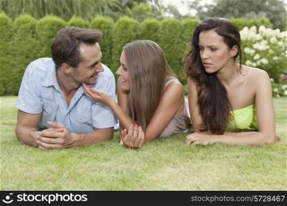Angry young woman looking at loving couple at park