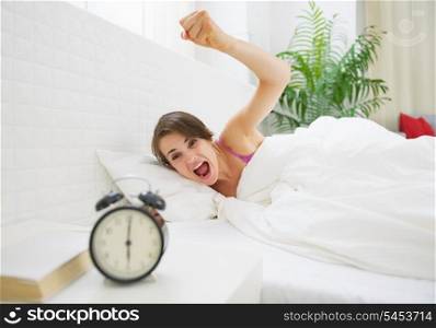 Angry young woman wants to break awakened her alarm clock