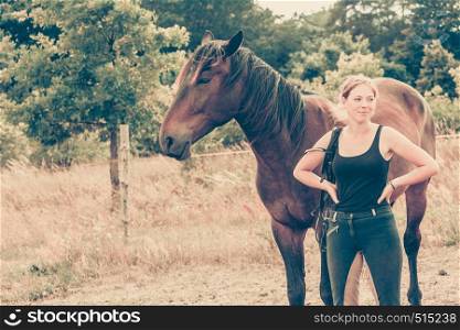 Animal and human love, equine concept. Jockey woman walking with horse on meadow. Jockey woman walking with horse on meadow
