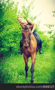 Animal, horsemanship concept. Young woman sitting on horse and leaning out of it. Young woman hugging and leaning out of house