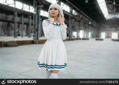 Anime girl, blonde woman with makeup. Cosplay, japanese culture, doll in dress on abandoned factory. Anime girl, blonde woman with makeup