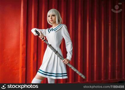 Anime style blonde girl with sword against red container. Cosplay woman, japanese culture, doll with blade