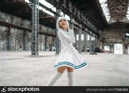 Anime style girl, blonde woman with makeup. Cosplay, japanese culture, doll in dress on abandoned factory. Anime style girl, doll in dress