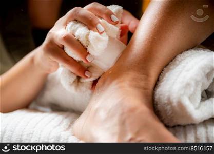 Ankle joint cryotherapy ice massage. Hands of a therapist placing ice directly onto a painful ankle to relieve pain, reduce inflammation and swelling and promote healing.. Ankle Joint Cryotherapy Ice Massage.
