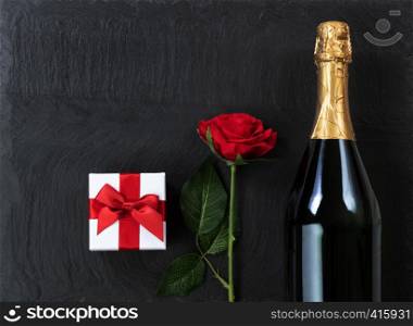 Anniversary background with champagne and gifts on natural black slate stone