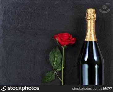 Anniversary background with red rose and champagne on natural black slate stone