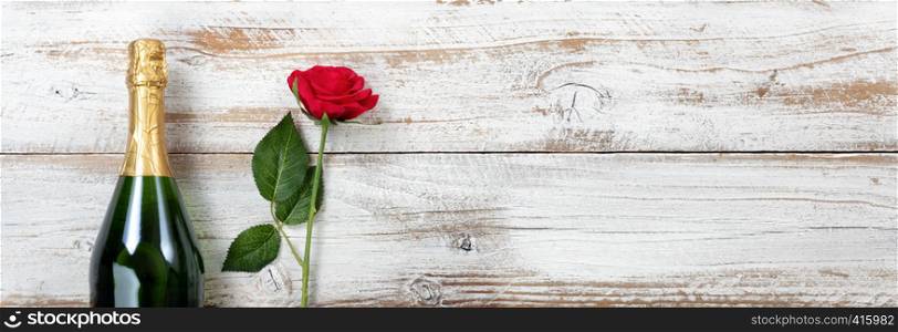 Anniversary background with red rose and champagne on white rustic wood