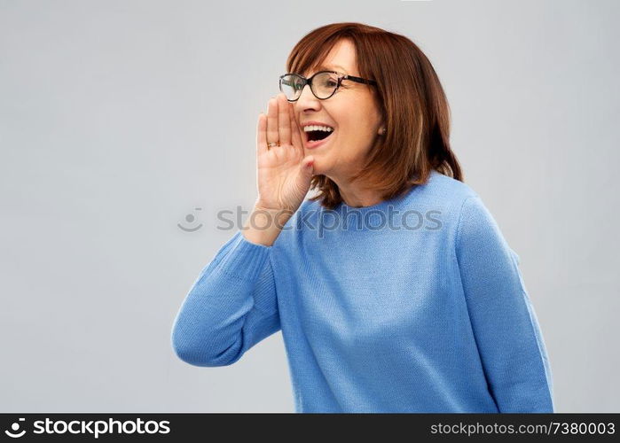 announcement and old people concept - senior woman in glasses calling over grey background. senior woman in glasses calling over grey