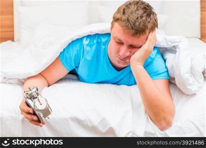 annoyed man with an alarm clock in the hands of suffering from insomnia