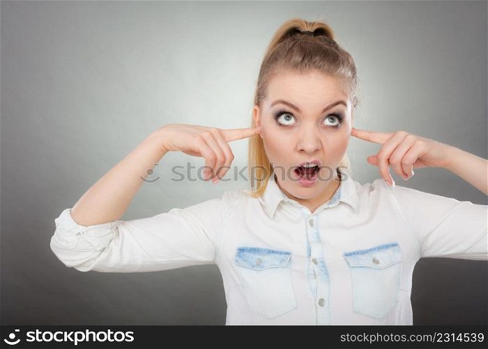 Annoyed woman closing ears with hands protecting from loud noise. Teen girl not wanting to hear, funny face expression. Girl not wanting to listen, closing ears with fingers