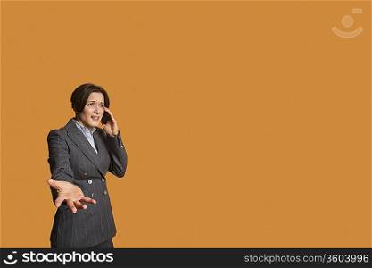 Annoyed woman talking on mobile phone with hand outstretched