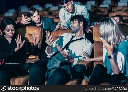 Annoying man talking on the mobile phone at the movie theater people in cinema is angry him
