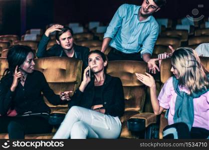 Annoying woman talking on the mobile phone at the movie theater people in cinema is angry her