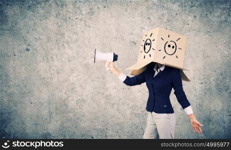 Anonymous announcement. Businesswoman wearing carton box on head and speaking in megaphone