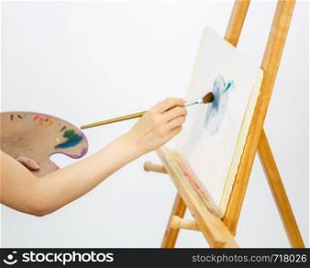 Anonymous artist painting at an easel, selective focus