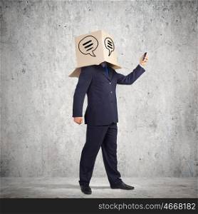 Anonymous call. Businessman using mobile phone wearing carton box on head